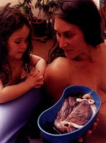 Мать показывает своей дочери плаценту после родов в воде. Это хорошая возможность для старших детей узнать что-то новое о родах